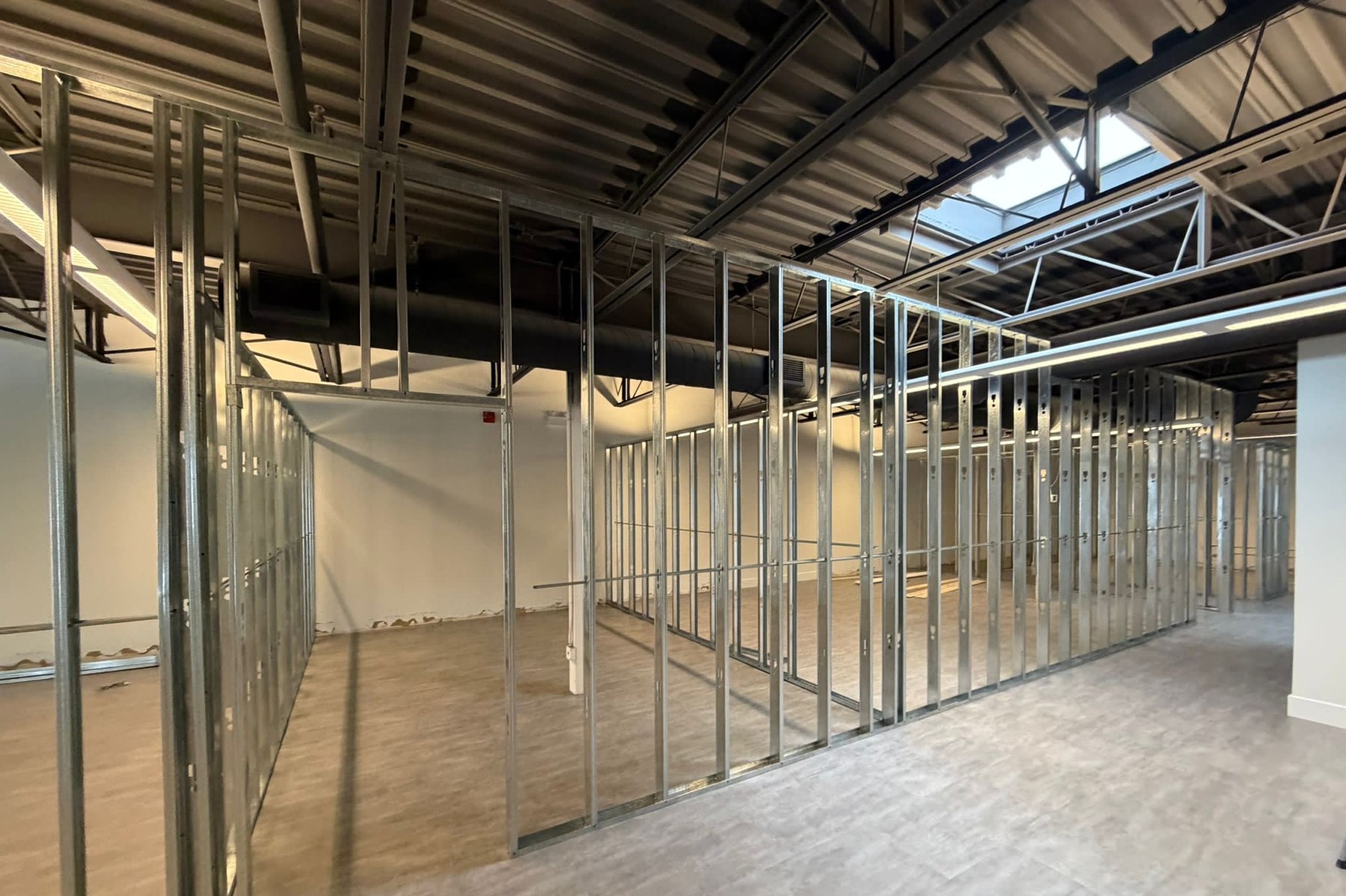 Partition framing beneath exposed steel deck and skylight