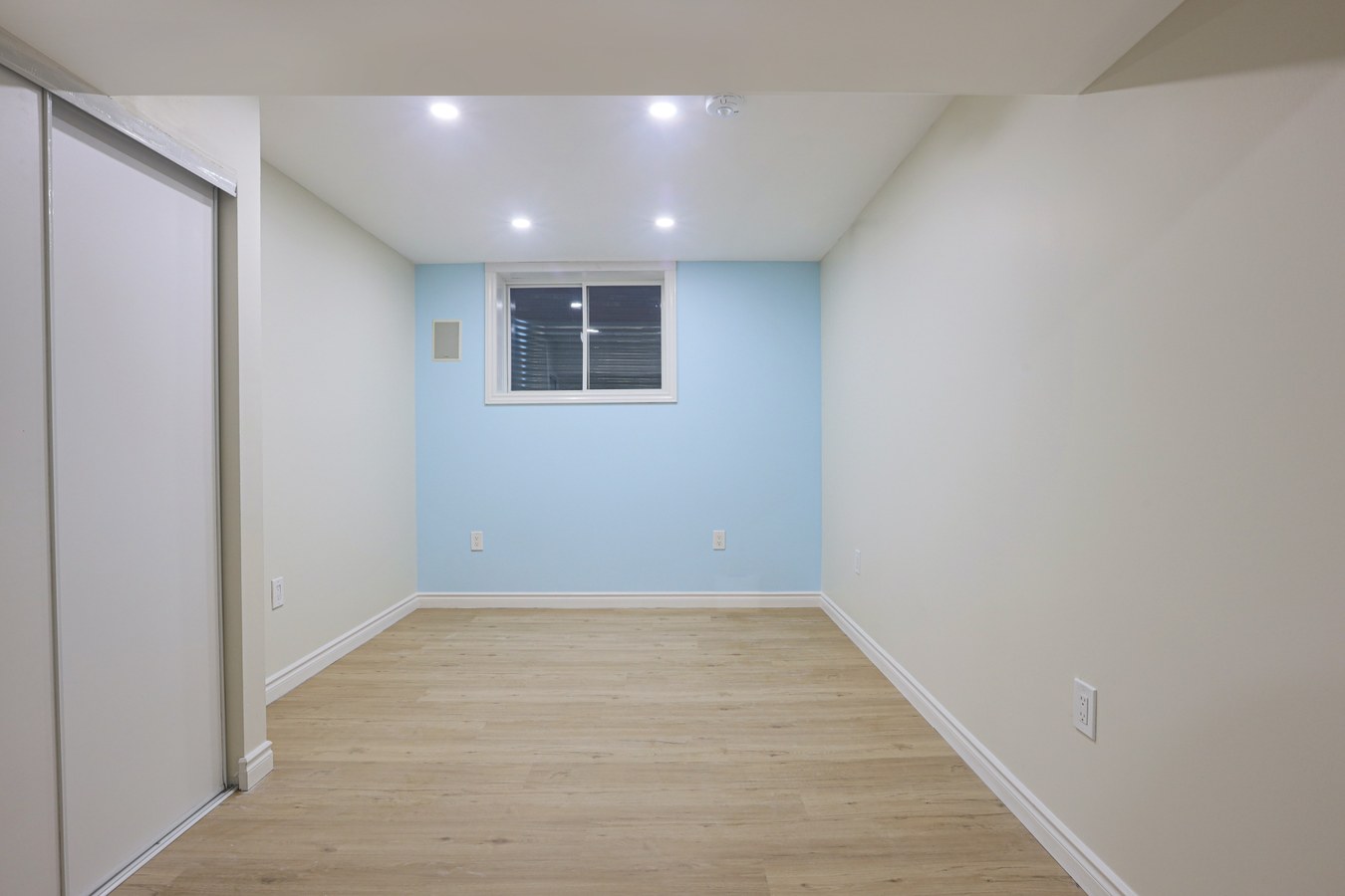 Finished basement with light blue accent wall and egress window